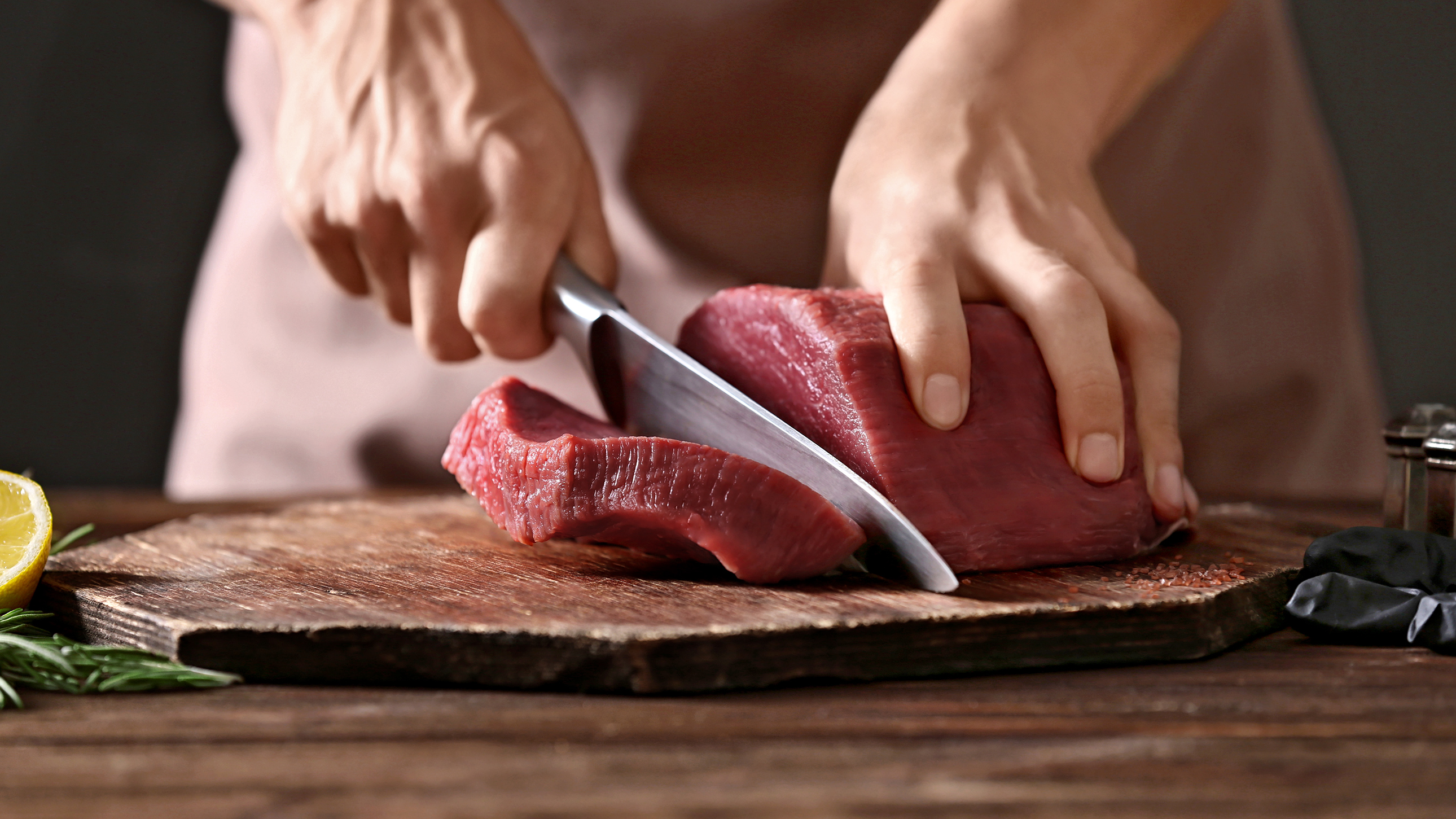 Jemand schneidet ein dickes Steak von einem Block Fleisch