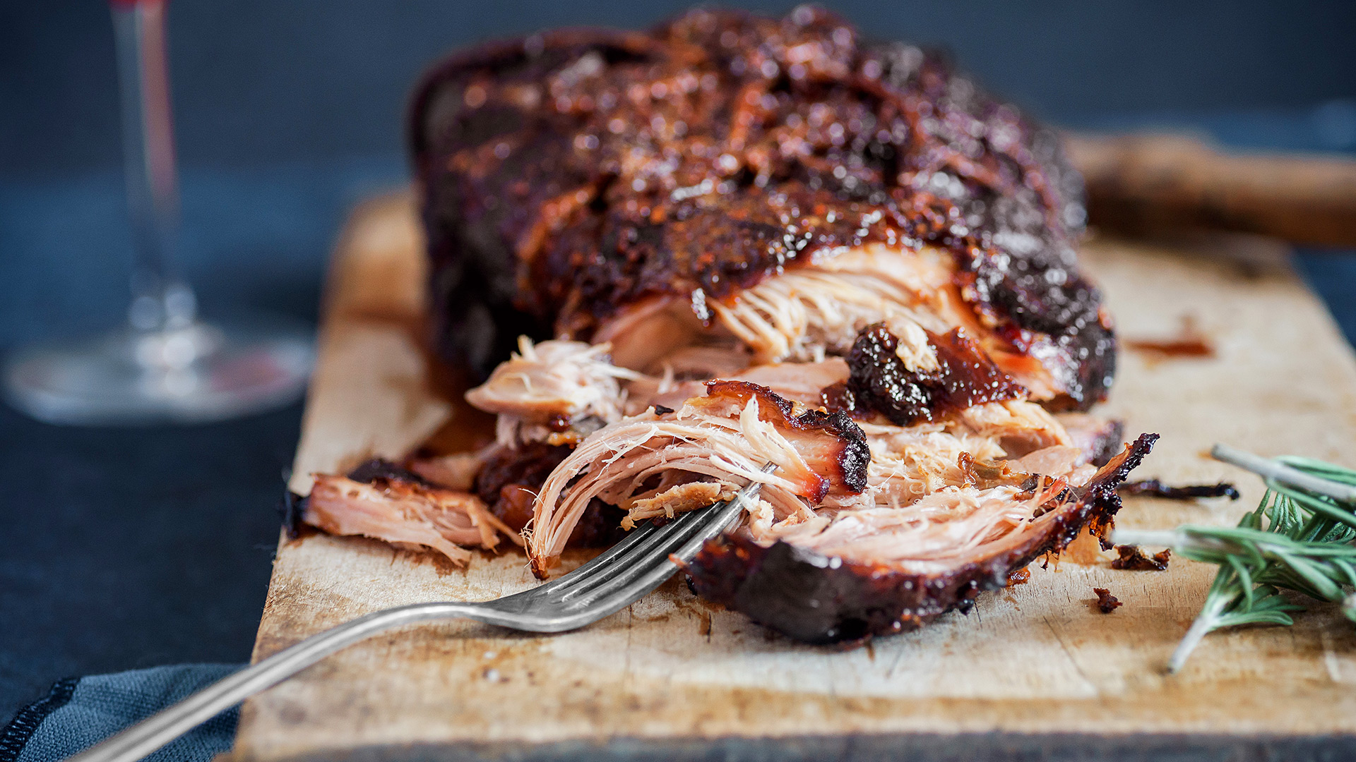 Pulled Pork auf den Holzbrett mit einer Gabel zerfleischt.