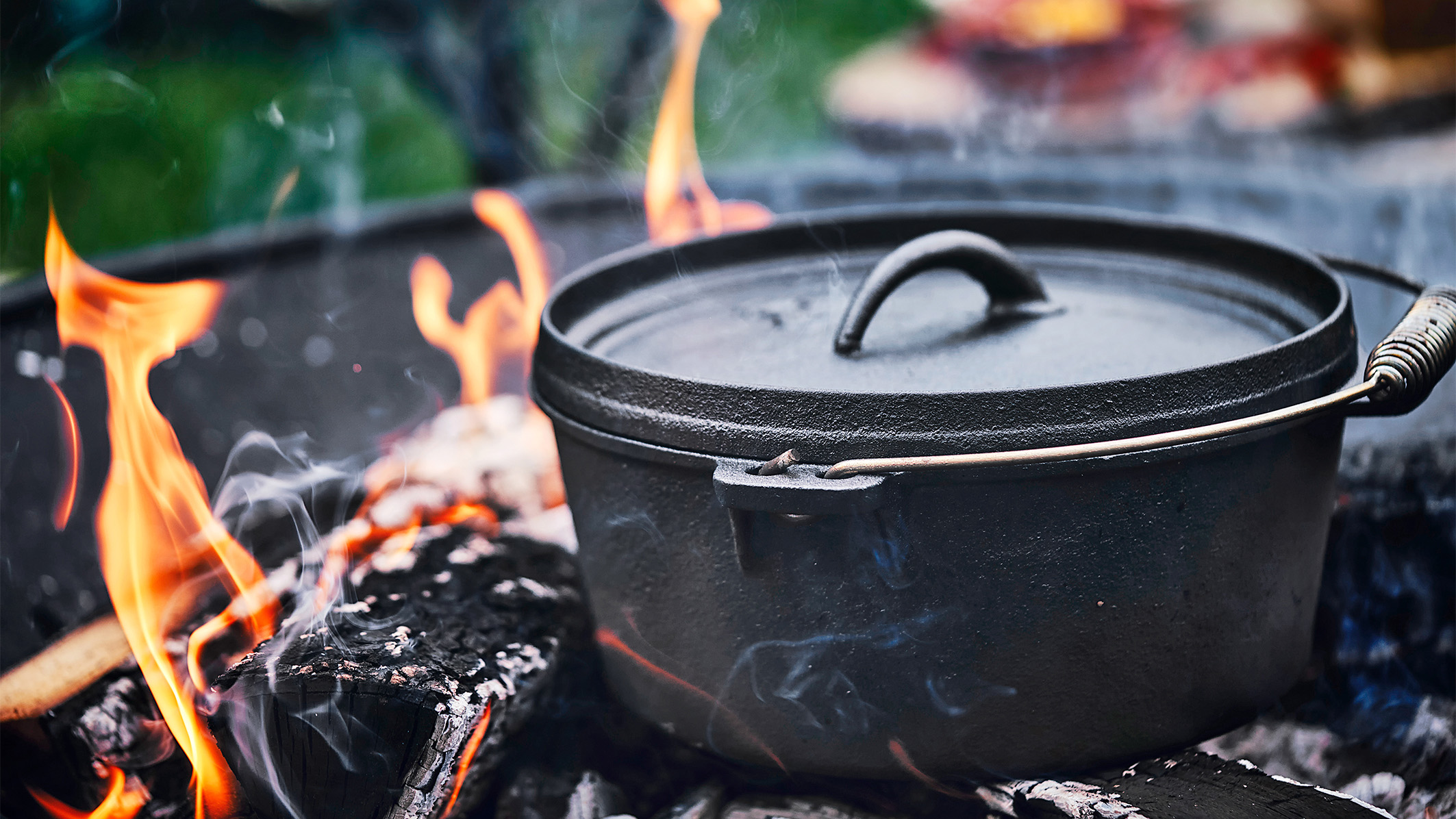 Ein schwarzer Dutch Oven steht am Feuer.